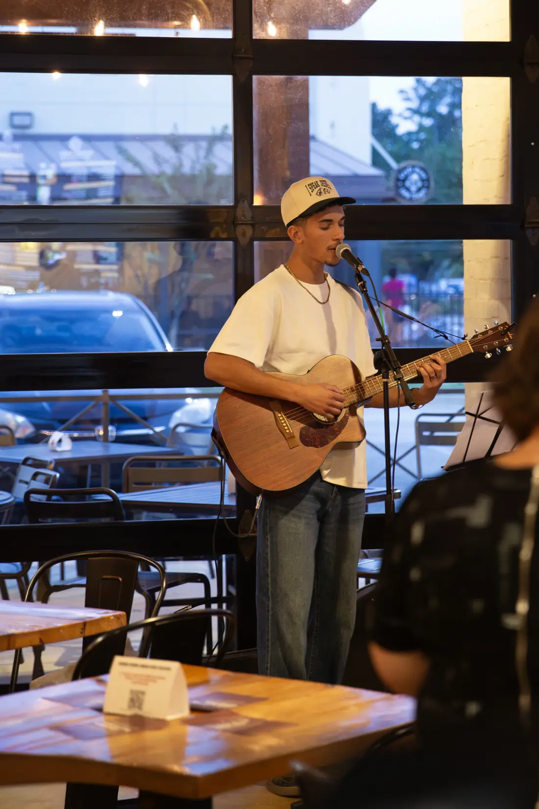 A man playing acoustic guitar and singing during a Church at the Woodlands gathering
